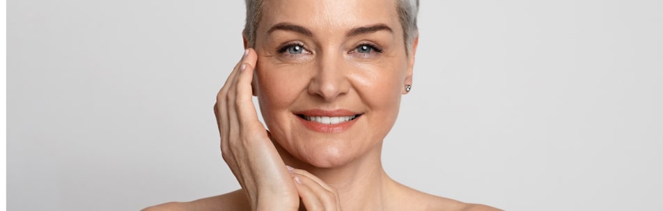 close-up image of an older woman touching the side of her face