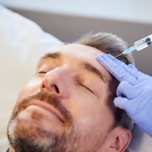 Giving Mature Male Patient Botox Injection In Forehead
