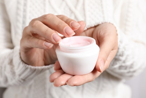 Woman holding jar of moisturizing cream closeup