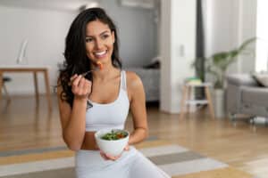 Beautiful woman with glowing skin eating a healthy bowl of salad.